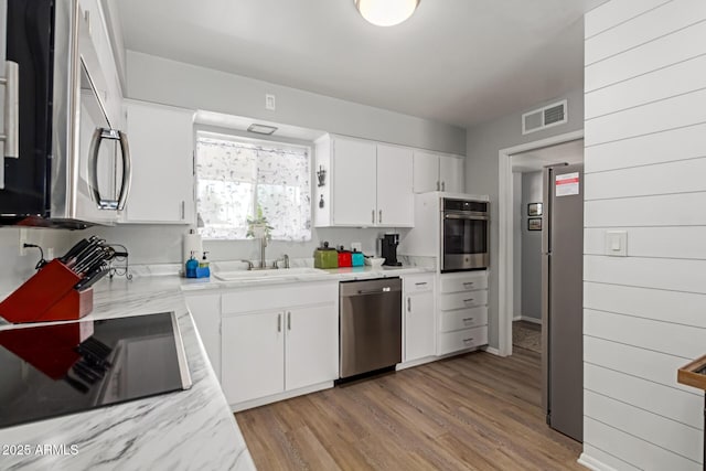 701 N 55th Pl, Mesa, AZ 85205 - kitchen featuring stainless steel appliances, a sink, white cabinets, light wood finished floors, and light stone countertops