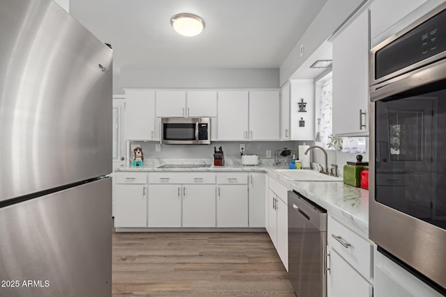 701 N 55th Pl, Mesa, AZ 85205 - kitchen with appliances with stainless steel finishes, a sink, light wood-type flooring, light countertops, and white cabinetry