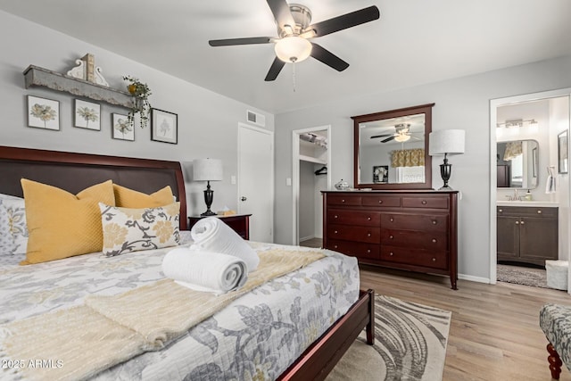 701 N 55th Pl, Mesa, AZ 85205 - bedroom featuring wood finished floors, a spacious closet, a sink, ensuite bath, and a ceiling fan