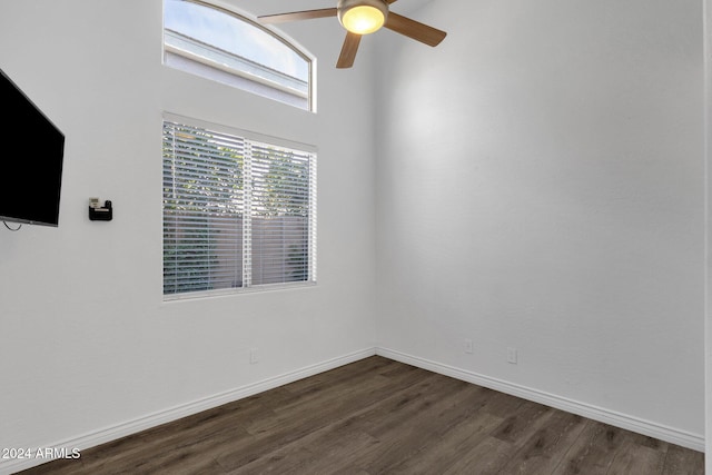 empty room with ceiling fan, dark wood-type flooring, and a high ceiling