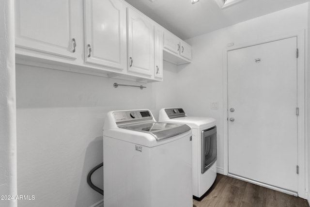 clothes washing area with washing machine and clothes dryer, dark hardwood / wood-style flooring, and cabinets