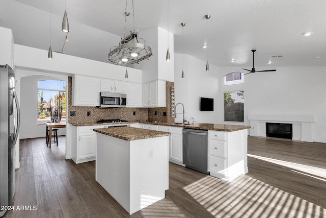 kitchen with a center island, high vaulted ceiling, white cabinets, hanging light fixtures, and stainless steel appliances