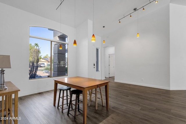 dining space featuring dark hardwood / wood-style floors, rail lighting, and high vaulted ceiling