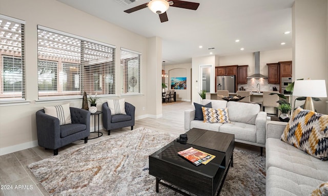 living room with ceiling fan, sink, and light hardwood / wood-style flooring