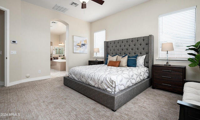 carpeted bedroom featuring multiple windows, connected bathroom, and ceiling fan