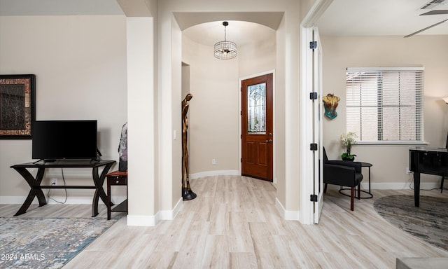 foyer entrance with a notable chandelier, a wealth of natural light, and light hardwood / wood-style flooring