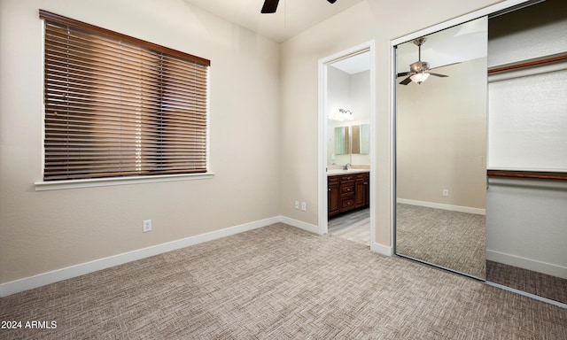 unfurnished bedroom featuring ensuite bath, light colored carpet, ceiling fan, sink, and a closet