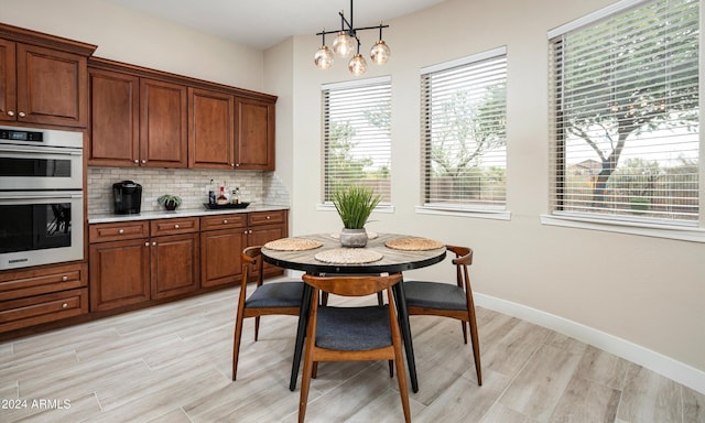 kitchen featuring tasteful backsplash, light hardwood / wood-style flooring, double oven, a chandelier, and decorative light fixtures