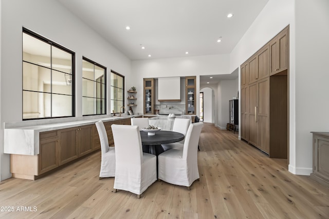 dining area featuring arched walkways, recessed lighting, and light wood-type flooring