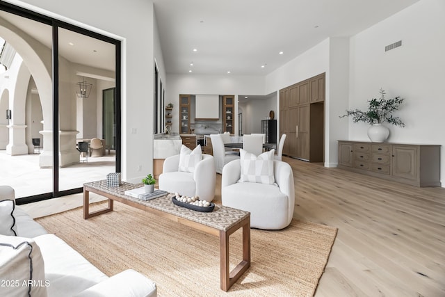 living room featuring arched walkways, visible vents, recessed lighting, and light wood-style floors