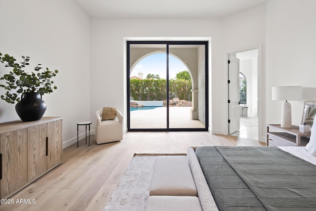 bedroom featuring access to exterior, baseboards, and light wood finished floors