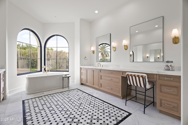 bathroom with recessed lighting, marble finish floor, a freestanding bath, and vanity