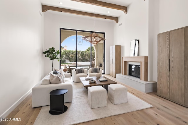 living area with beam ceiling, light wood-style floors, and a chandelier