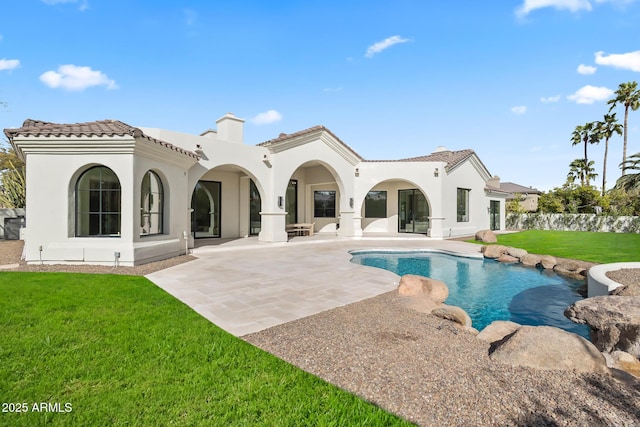 rear view of property featuring a fenced in pool, stucco siding, a tiled roof, a patio area, and a lawn