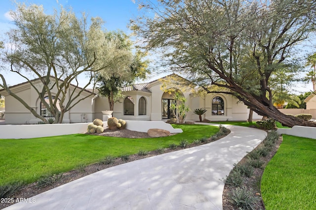 mediterranean / spanish-style house featuring a front lawn and stucco siding