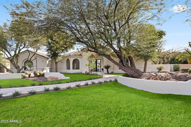 mediterranean / spanish house with stucco siding and a front lawn