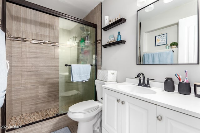 bathroom featuring toilet, vanity, and a shower with door