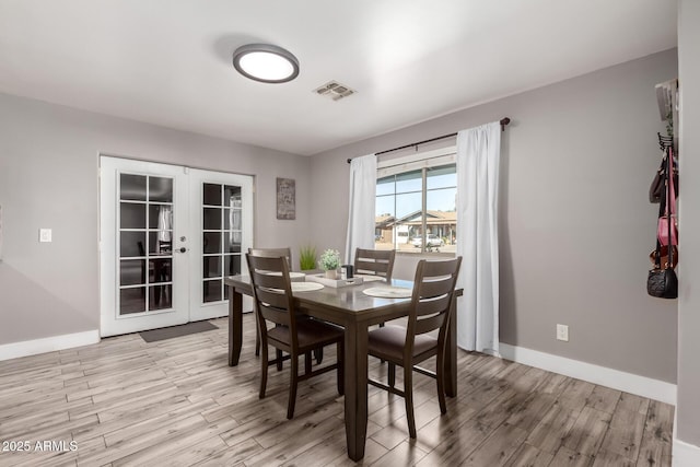 dining room with french doors and light hardwood / wood-style flooring