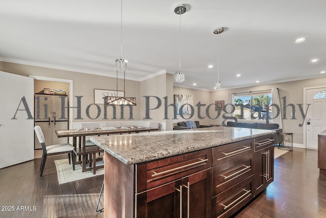 kitchen featuring crown molding, dark hardwood / wood-style floors, a kitchen island, pendant lighting, and light stone countertops