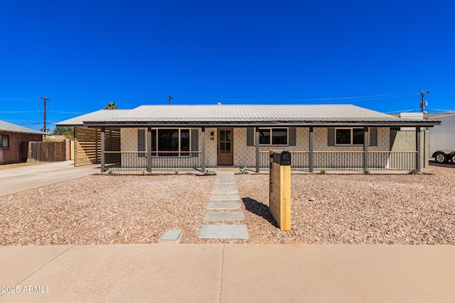 single story home featuring metal roof, a porch, and fence