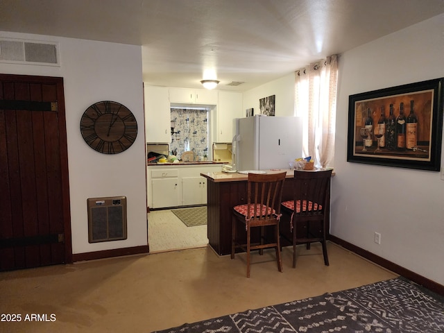 2315 N US Highway 93, Wickenburg, AZ 85390 - kitchen featuring freestanding refrigerator, heating unit, a peninsula, white cabinets, and a kitchen breakfast bar