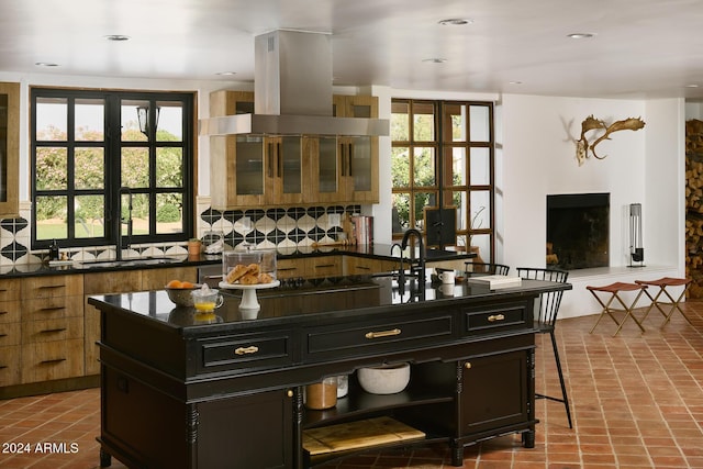 kitchen featuring island exhaust hood, a kitchen island, decorative backsplash, and a wealth of natural light