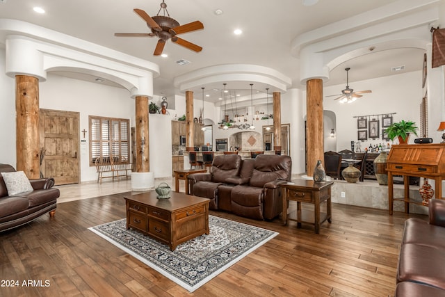 living room featuring hardwood / wood-style floors, ceiling fan, and ornate columns