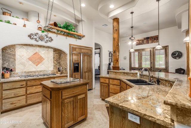 kitchen with sink, decorative light fixtures, stainless steel gas stovetop, paneled built in fridge, and a center island