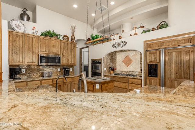 kitchen featuring stainless steel appliances, sink, tasteful backsplash, and light stone countertops