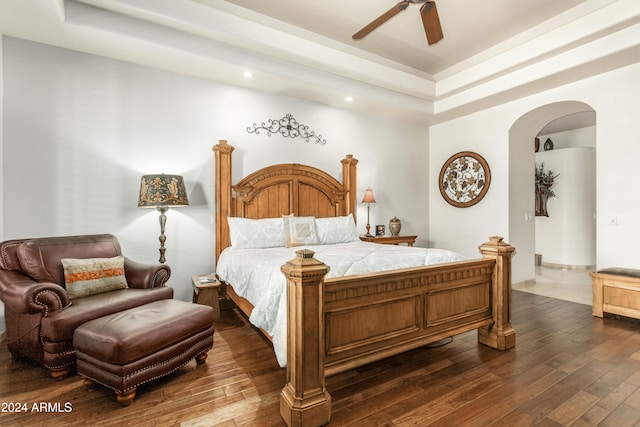 bedroom with ceiling fan, dark hardwood / wood-style floors, and a raised ceiling