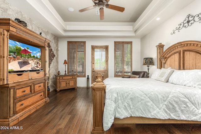 bedroom featuring dark wood-type flooring, ceiling fan, and a raised ceiling