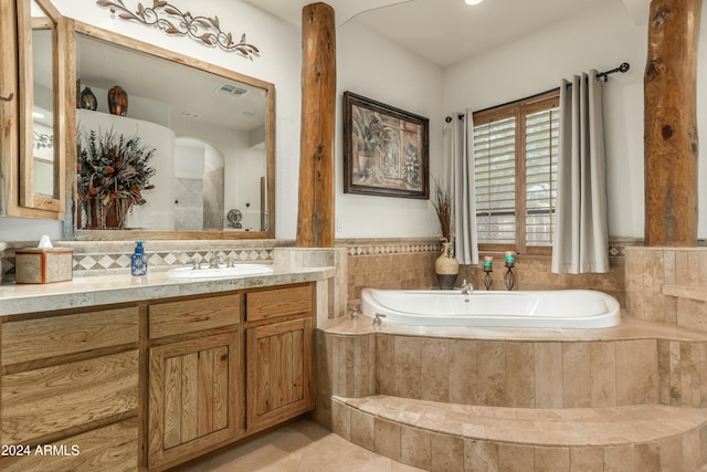 bathroom featuring tiled bath and vanity