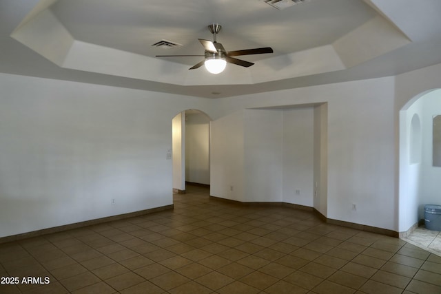 unfurnished room with ceiling fan, light tile patterned floors, and a tray ceiling