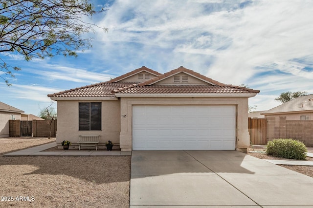 view of front facade featuring an attached garage, fence, a tile roof, concrete driveway, and stucco siding