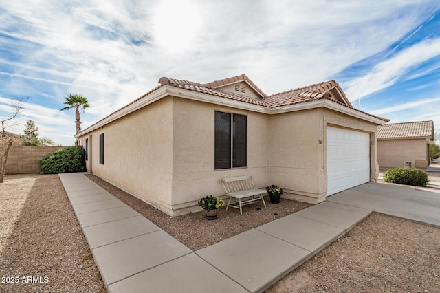 view of front of house with concrete driveway, an attached garage, a tile roof, and stucco siding