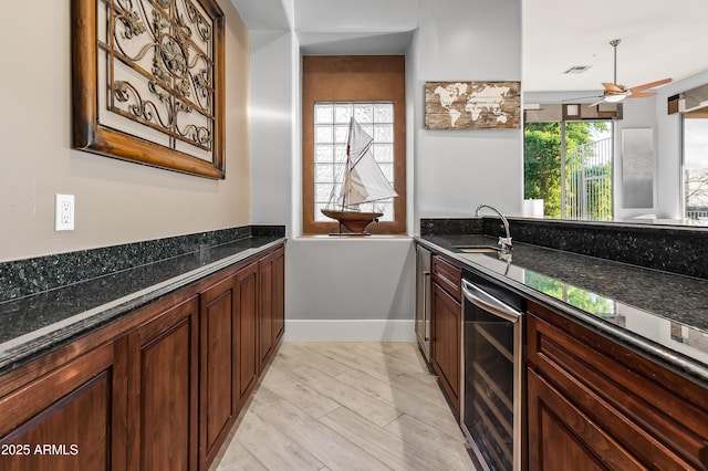 kitchen with beverage cooler, sink, and dark stone countertops