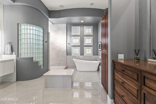 bathroom with vanity, a bathing tub, and plenty of natural light