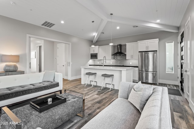 living room with dark hardwood / wood-style flooring, sink, and vaulted ceiling with beams