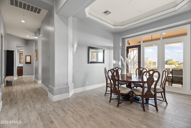 dining room featuring a tray ceiling and light hardwood / wood-style flooring