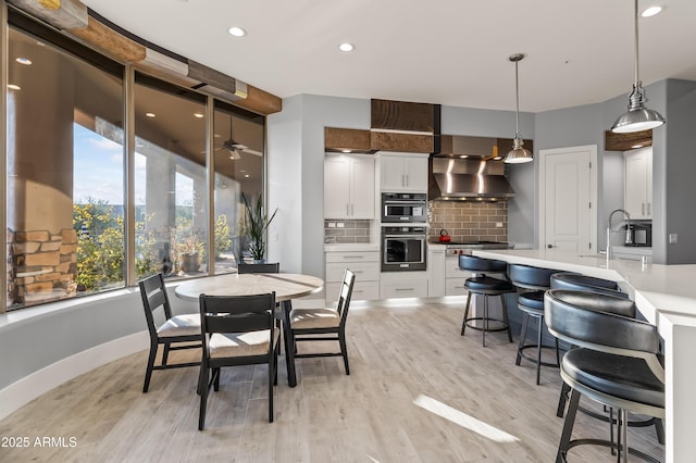 dining space with ceiling fan, sink, and light wood-type flooring