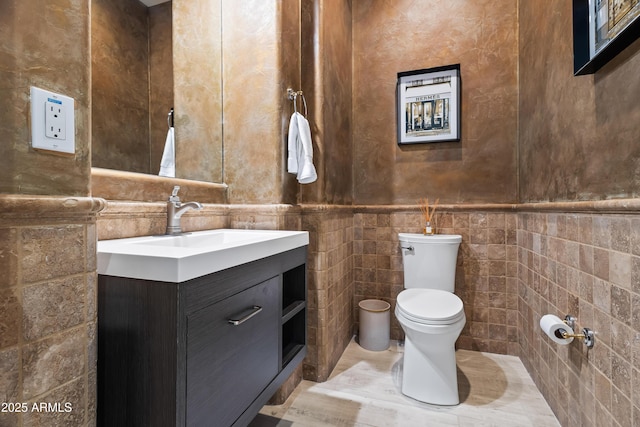 bathroom featuring vanity, tile walls, and toilet