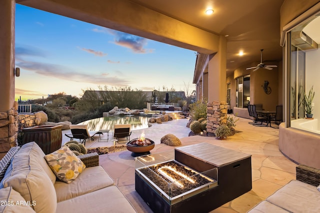 patio terrace at dusk with an outdoor living space with a fire pit and ceiling fan