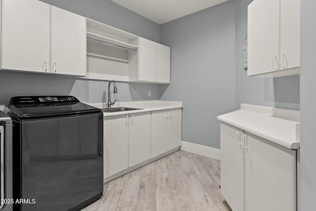 clothes washing area featuring cabinets, sink, and light wood-type flooring