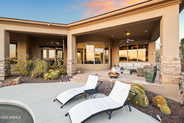 patio terrace at dusk with an outdoor living space with a fire pit and ceiling fan