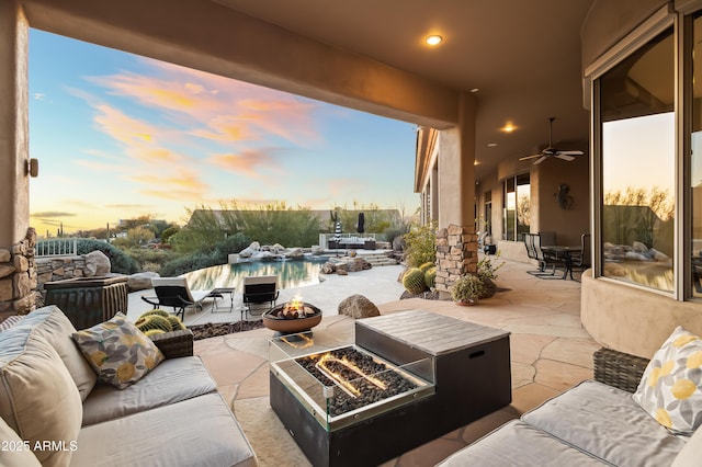 patio terrace at dusk featuring an outdoor living space with a fire pit and ceiling fan