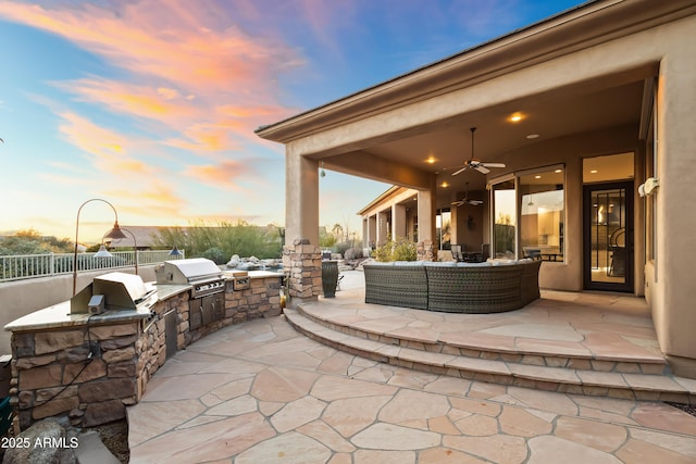 patio terrace at dusk featuring area for grilling and ceiling fan