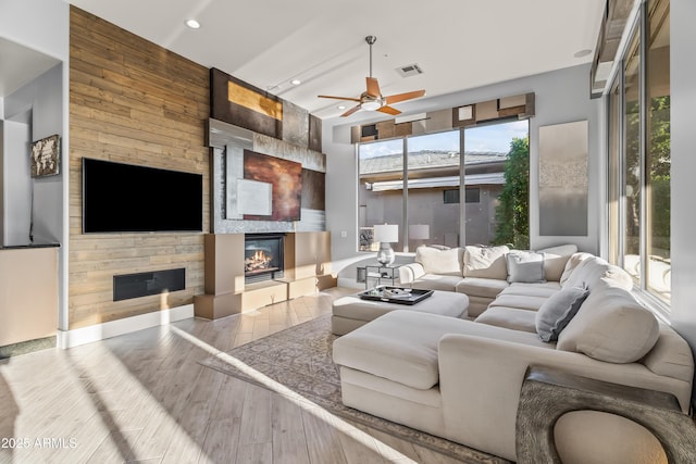 living room with ceiling fan, a fireplace, and light hardwood / wood-style floors