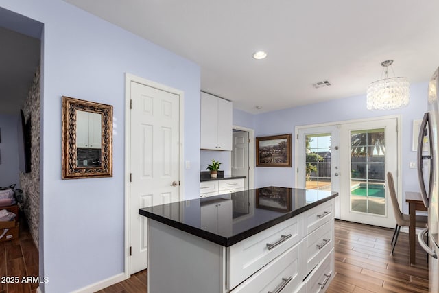 kitchen featuring pendant lighting, dark wood-type flooring, white cabinetry, and a kitchen island