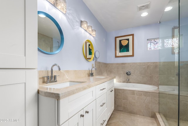 bathroom featuring tile patterned floors, a relaxing tiled tub, and vanity