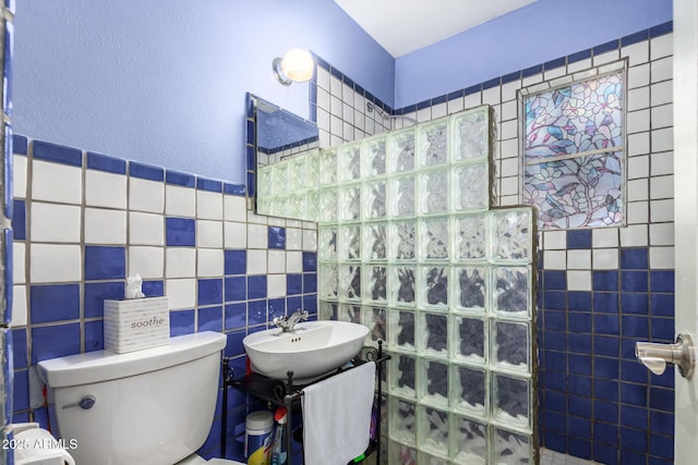 bathroom with toilet, sink, tile walls, and walk in shower